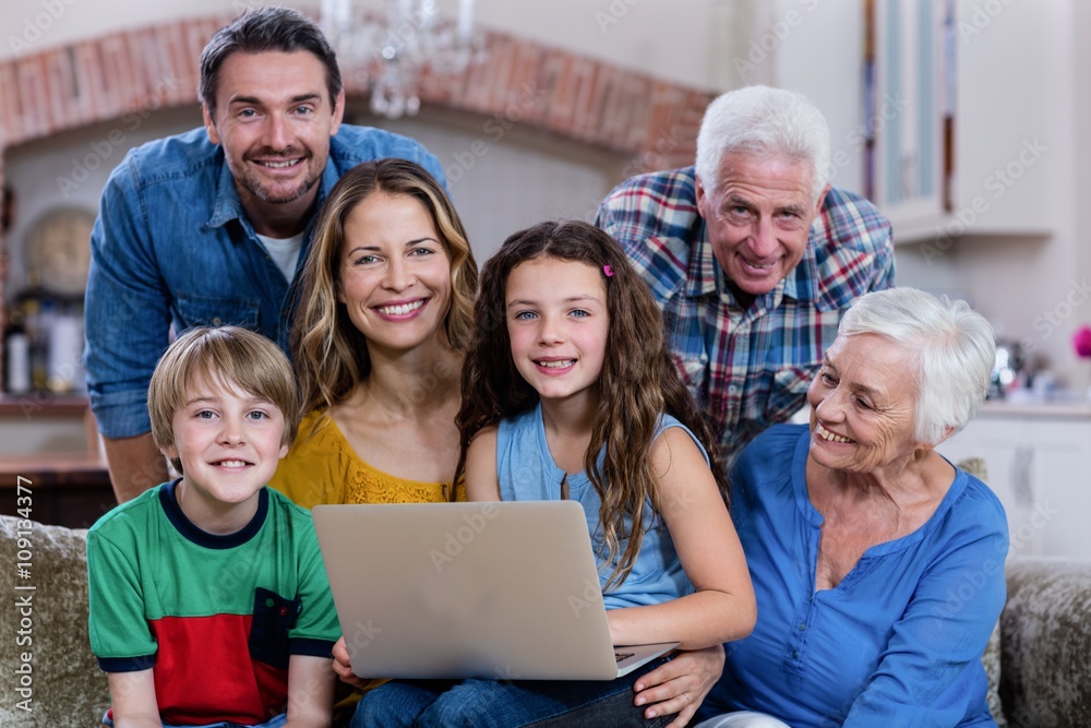 Multi-generation family sitting on sofa and using laptop Multi-generation family sitting on sofa and using laptop