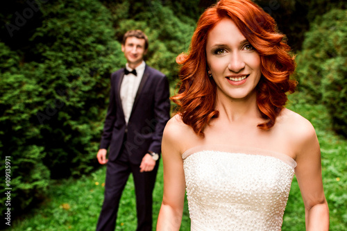 Redhead curly bride and groom behind her © IVASHstudio