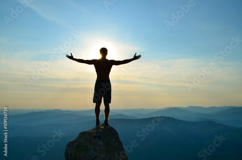man stands on top of a mountain with open hands photo