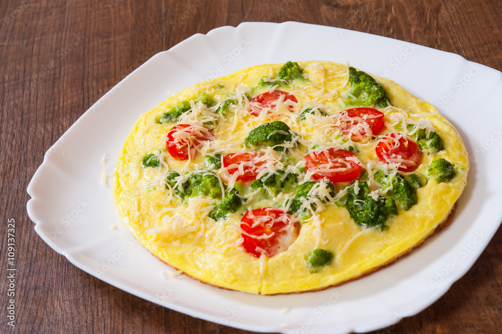 omelet with tomato, broccoli and cheese in a plate on wooden table omelet with tomato, broccoli and cheese in a plate on wooden table