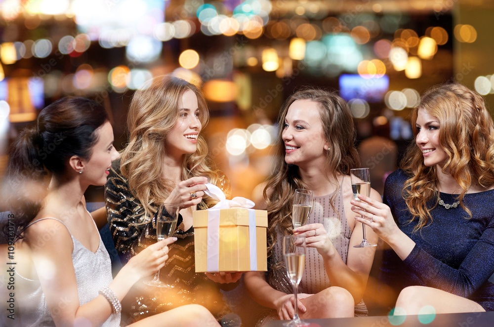 happy women with champagne and gift at night club happy women with champagne and gift at night club