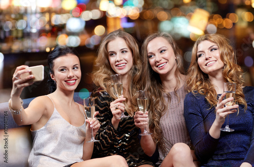 women with champagne taking selfie at night club