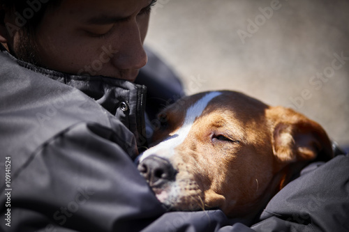 man holding sleepy puppy dog closeup selective focus concept social issue homelessness poverty animal rights
