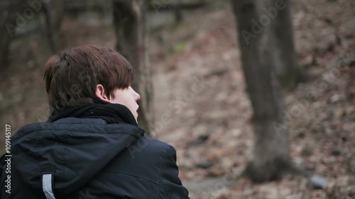 Back view of depressed young man sitting alone outdoors, having sad thoughts