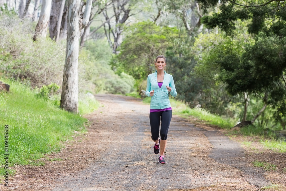 Cheerful young woman jogging in forest Cheerful young woman jogging in forest
