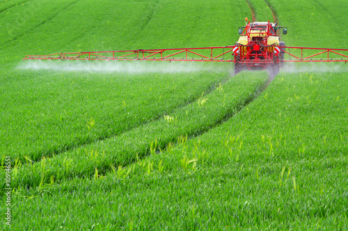 Traktor mit Feldspritze beim Ausbringen von Pflanzenschutzmittel photo