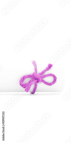 Handmade pink string bow tied on white letter roll isolated