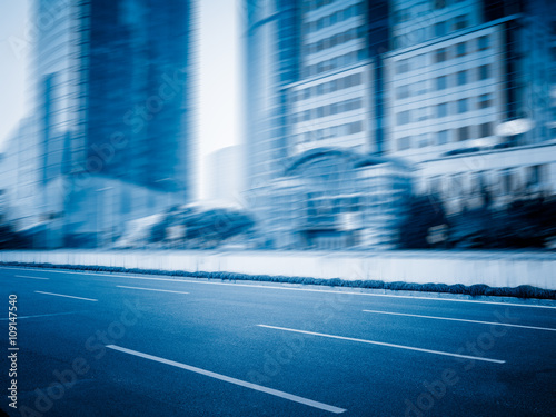 clean city road against blurred office buildings blue toned image.