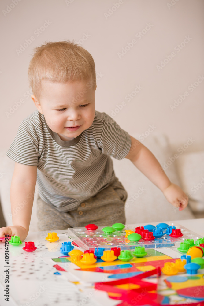Cute preschooler child boy plays with mosaic at home. A blond little toddler playing in kid's room. Leisure activities. indoors. Boy sorting colorful children's plastic mosaic. Development. Cute preschooler child boy plays with mosaic at home. A blond little toddler playing in kid's room. Leisure activities. indoors. Boy sorting colorful children's plastic mosaic. Development.