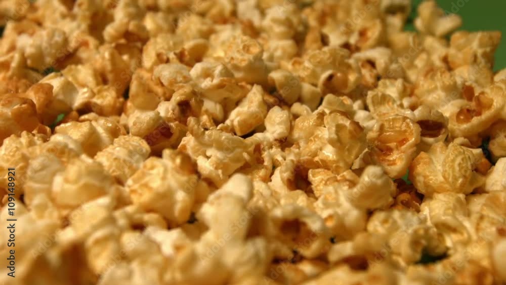 Popcorn on a green background. Slow motion. Close-up. Vertical pan. 3 Shots