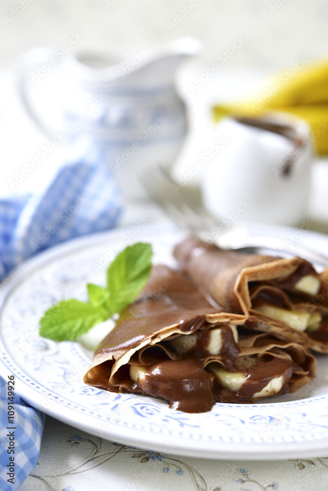 Chocolate pancakes with banana and chocolate sauce.