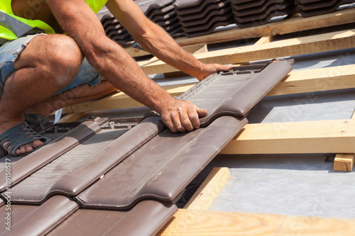 Bild auf Leinwand Hands of roofer laying tile on the roof