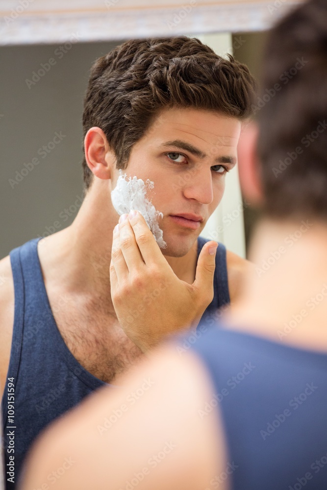 Young man applying shaving foam on his face Young man applying shaving foam on his face