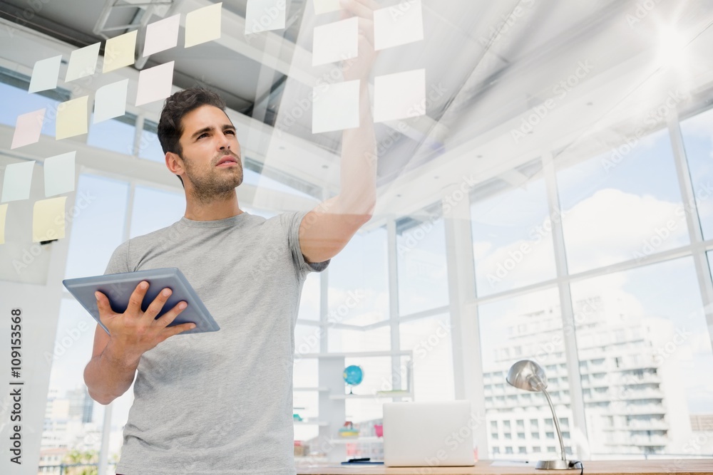 Man holding digital tablet and looking at sticky notes Man holding digital tablet and looking at sticky notes
