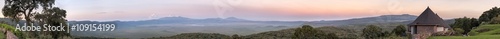 Panoramic view of huge Ngorongoro caldera (extinct volcano crater) with lodge hotel bungalows against sunrise glow background. Great Rift Valley, Tanzania, East Africa. 