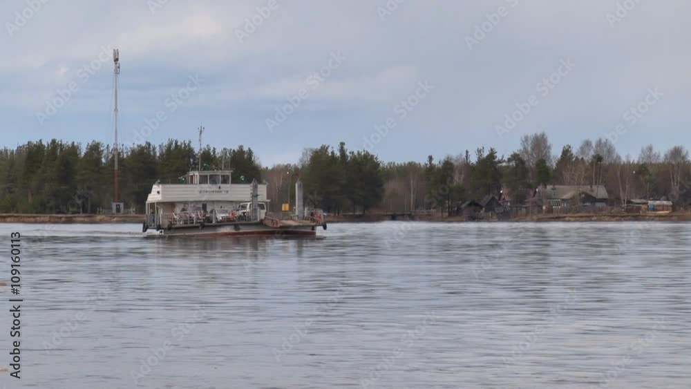 Ferry Transports Cars on River. The ferry transports vehicles on the river during the spring flood. The ship blows over. On the shore of the river lies the village
Ferry Transports Cars on River. The ferry transports vehicles on the river during the spring flood. The ship blows over. On the shore of the river lies the village
