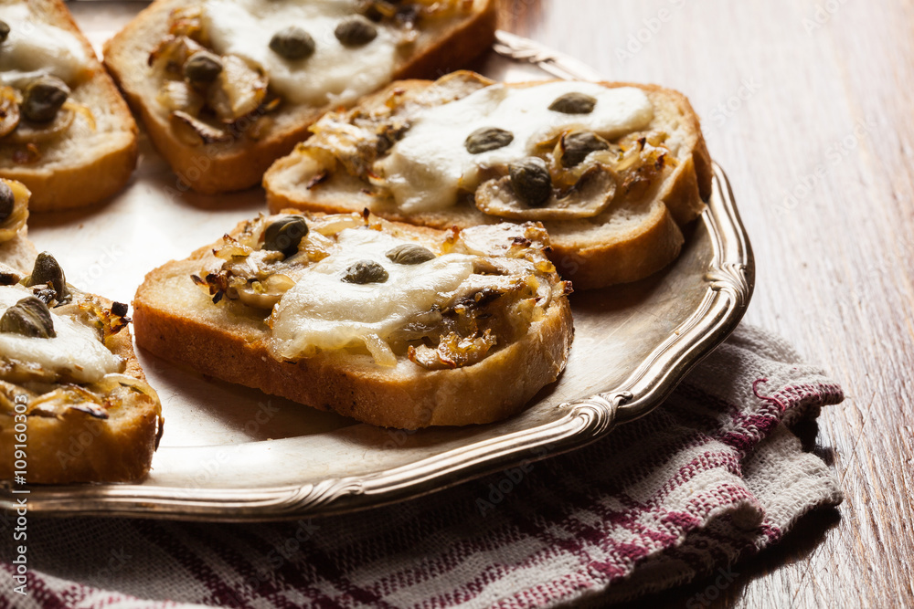 Crostini with fried mushrooms, onion and mozzarella cheese