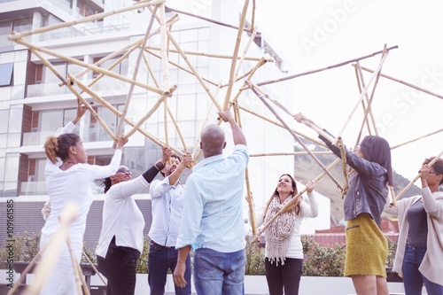 Low angle view of colleagues in team building task lifting building wooden structure