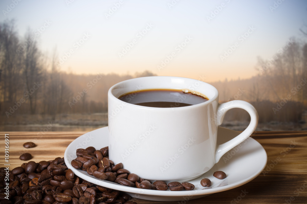 Coffee in cup on wooden table opposite blurred background. Colla