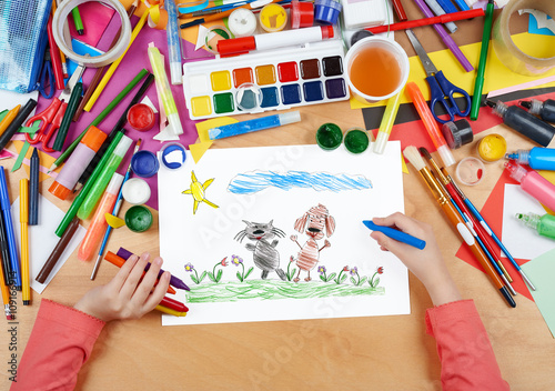 child drawing cat and dog friends walk on grass  top view hands with pencil painting picture on paper  artwork workplace