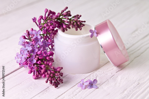 Pot of moisturizing cream with lilac flowers