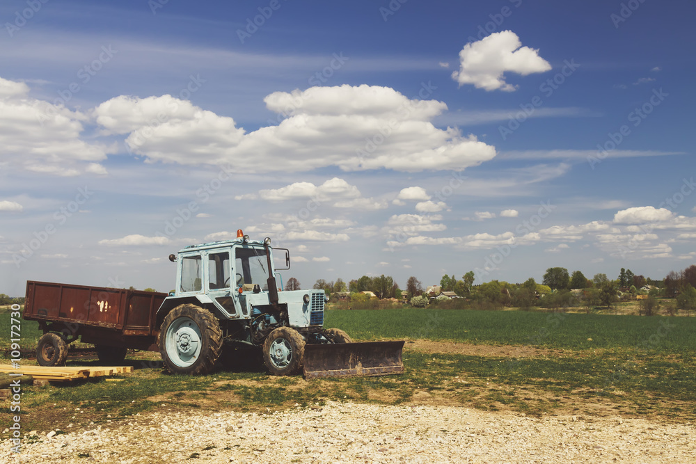 Fototapeta premium Tractor in the field with blue sky and clouds