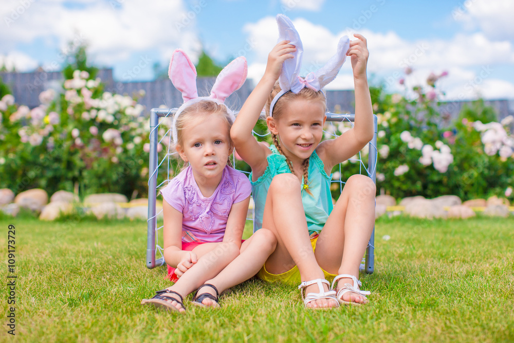 Two adorable little sisters wearing bunny ears on Easter day outdoors Two adorable little sisters wearing bunny ears on Easter day outdoors
