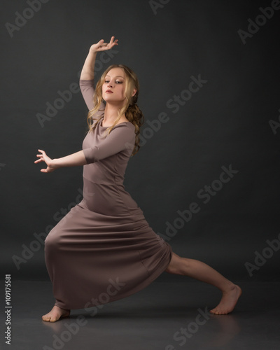 Contemporary dance. Beautiful elegant woman dances on gray background