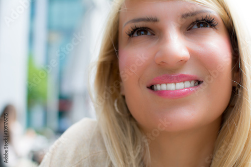 Beautiful girl with long blonde hair outdoor. Smile on her face. Sunny natural light. Selective focus.