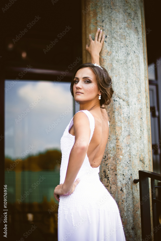 Fototapeta premium Beautiful sexy brunette bride in white dress walking up stairs
