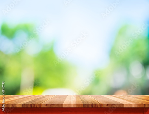 Empty brown wood table top with sun and blur green tree bokeh ba