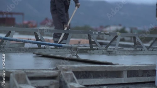 Poured concrete getting flattened by workers and industrial tools or equipment at the construction site. Slow motion close up  shot. photo