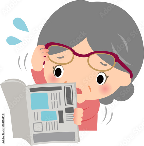 新聞を読む老眼のシニア女性