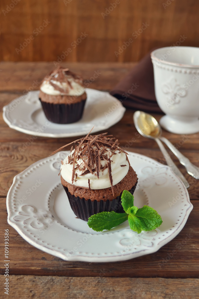 Chocolate cupcakes with cream and chocolate on a wooden backgrou Chocolate cupcakes with cream and chocolate on a wooden backgrou