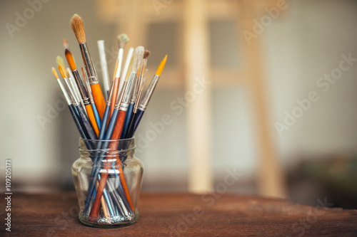 Paintbrushes in glass jar in artist's studio
