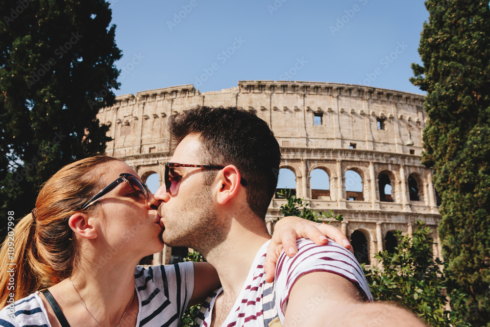 Young couple taking a selfie in Rome in front of the Colosseum