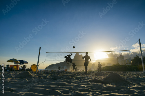 Silhouettes of Brazilians playing futevolei (footvolley) against a sunset backdrop of Dois Irmaos Two Brothers Mountain on Ipanema Beach, Rio de Janeiro Brazil 
