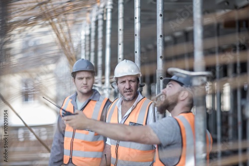 Fotografie Site manager and builders pointing to steel rods on  construction site