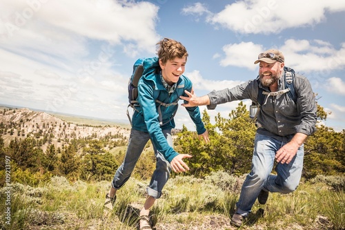 Father and teenage son chasing each other on hiking trip, Cody, Wyoming, USA photo