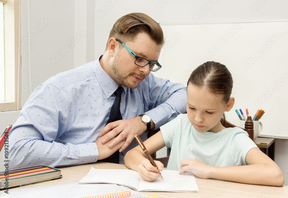 Young teacher and schoolgirl writing in classroom Young teacher and schoolgirl writing in classroom