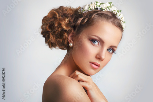 Beautiful young girl with a floral ornament in her hair.Beautiful Woman Touching her Face. Youth and Skin Care Concept on white background