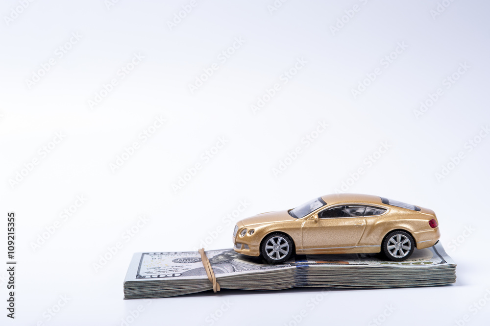 Golden toy car on dollars stack with rubberband