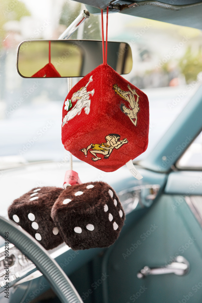 Fluffy dice hanging from rear-view mirror in car Stock Photo