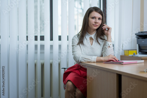 sexy girl in the office near the window reading a document on the table