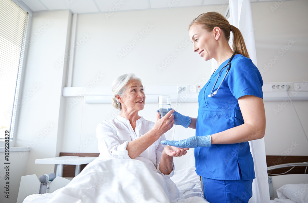 Obraz premium nurse giving medicine to senior woman at hospital