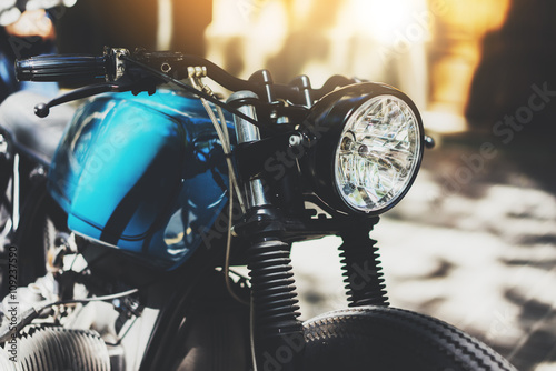 Close-up of a vintage cafe-racer motorcycle, details of hipster motorbike outdoors, flare light, film effect