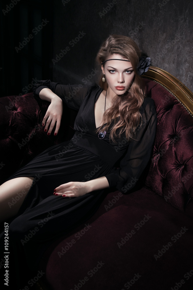 Sexy young woman in black dress lying on red vintage couch Sexy young woman in black dress lying on red vintage couch