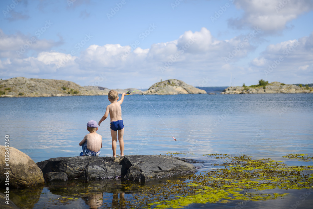 Rear view of siblings fishing at sea Rear view of siblings fishing at sea