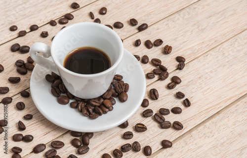 Cup of coffee beans with a spoon and saucer on a white background with the outline of more coffee beans