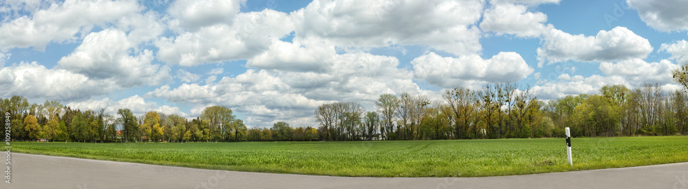 Rural landscape with a road panorama.Blue cloudy sky over a green meadow near Munich, Germany